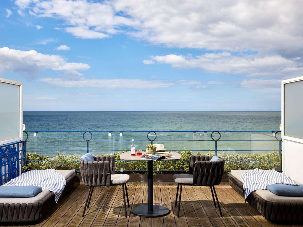 a balcony with a table and chairs and the ocean at Le Grand Hotel de Cabourg - MGallery Collection in Cabourg
