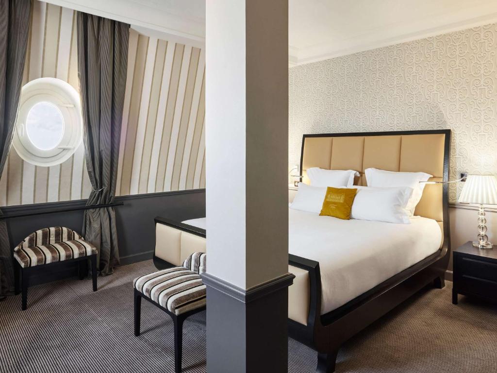 a hotel room with a bed and a chair at Le Grand Hotel de Cabourg - MGallery Collection in Cabourg