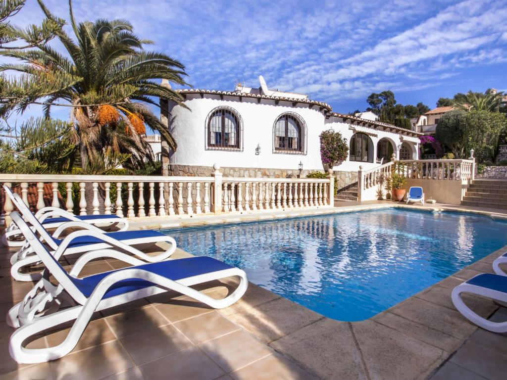 a villa with a swimming pool and two lounge chairs at Holiday Home Bizet by Interhome in Jávea