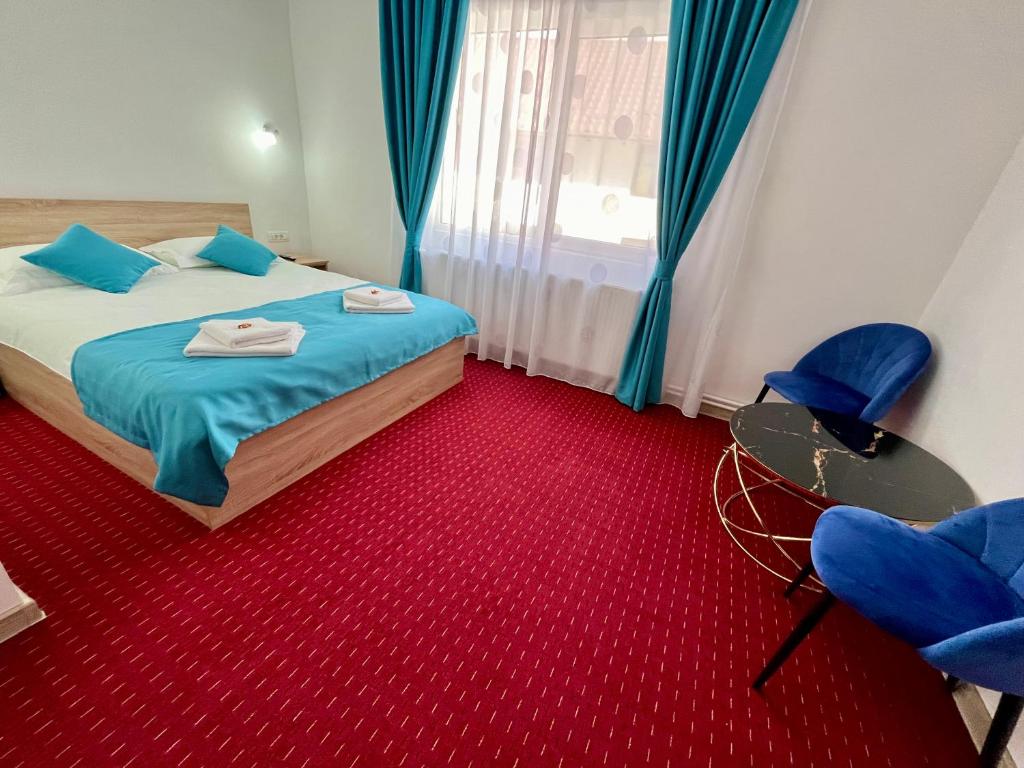 a bedroom with a bed and two blue chairs at Milea's Guesthouse in Bran