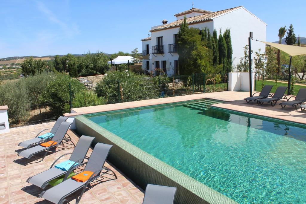 una piscina con sillas y una casa en Arriadh Hotel, en Ronda