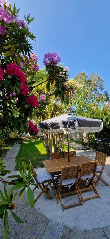 une table et des chaises avec un parasol et quelques fleurs dans l'établissement La Verrière, à Cherbourg en Cotentin