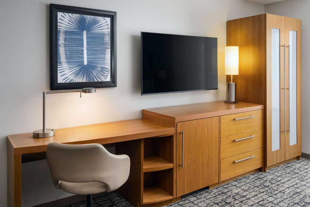 uma secretária com uma televisão e uma cadeira num quarto em Hyatt Place Canton em Lake Cable