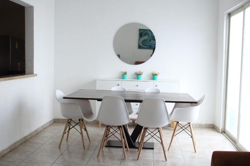 a dining room table with white chairs and a mirror at Amplia Casa en Sector Viñedos (factura) in Torreón