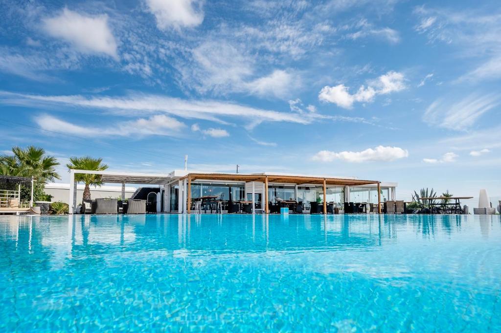 una grande piscina di acqua blu con un edificio di Smy Santorini Suites & Villas a Pyrgos