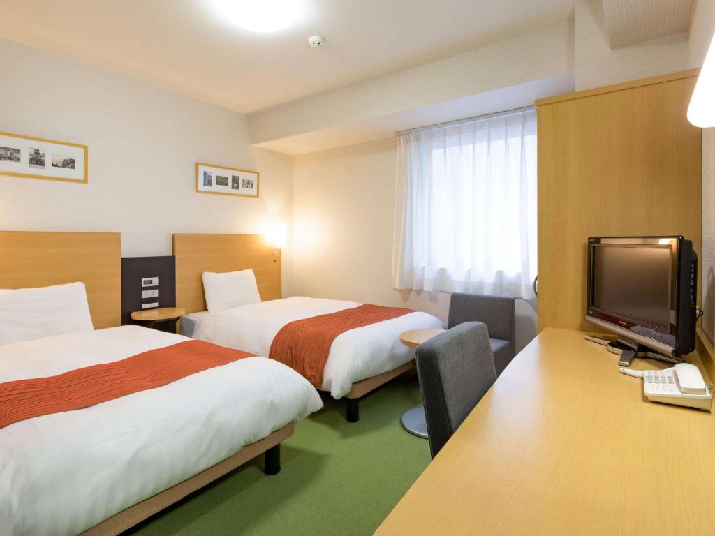 Comfort Hotel Yamagata في ياماغاتا: غرفة فندقية بسريرين وتلفزيون بشاشة مسطحة