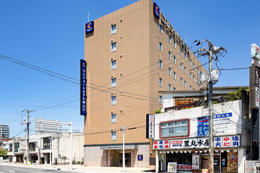 Comfort Hotel Shin Yamaguchi في ياماغوتشي: مبنى من الطوب الطويل مع علامات على جانبه