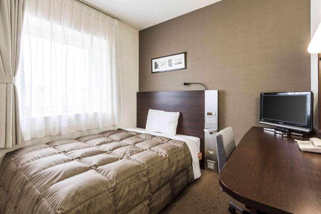 una camera d'albergo con letto e scrivania con computer di Comfort Hotel Kitami a Kitami