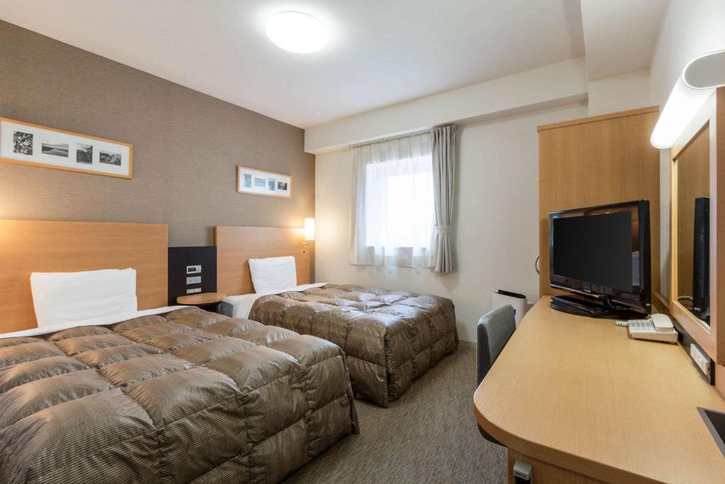 Comfort Hotel Kitakami في كيتاكامي: غرفة فندقية بسريرين ومكتب