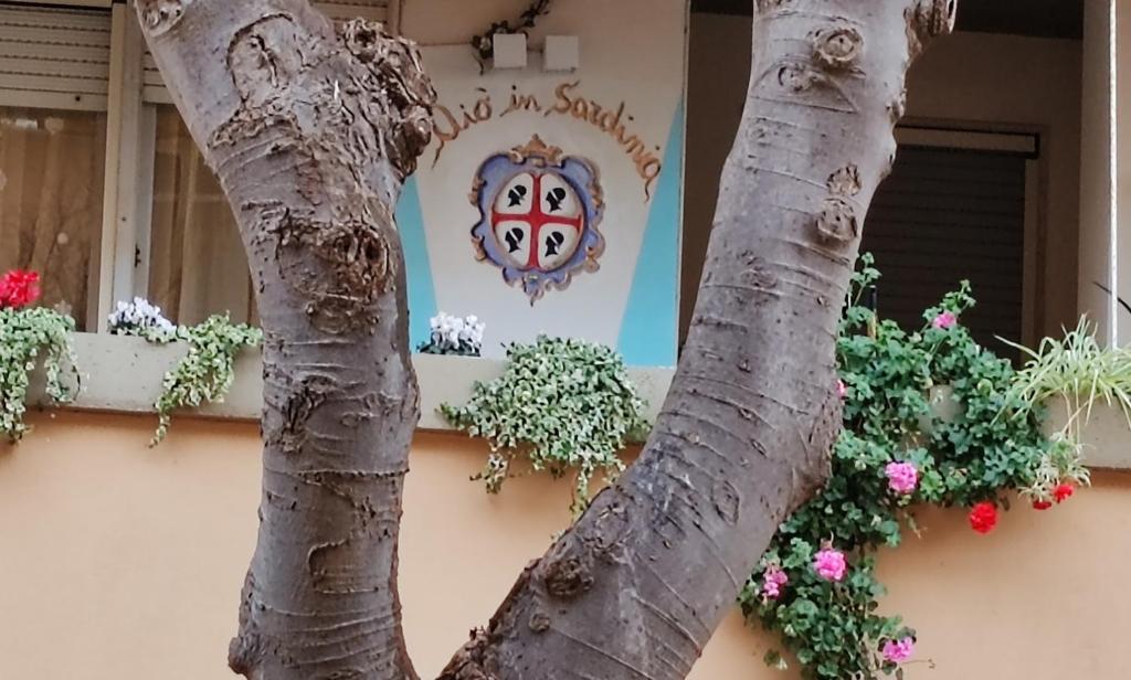 una señal en el lado de un edificio con flores en Elisart Guest House, en Alghero