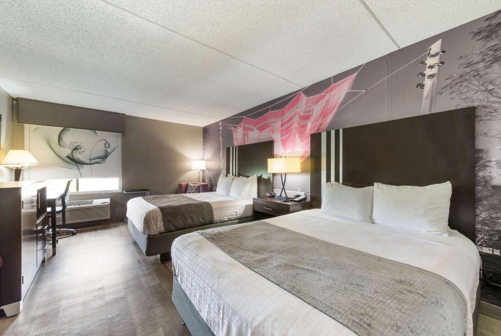 um quarto de hotel com duas camas e um quadro na parede em Clarion Pointe Greensboro Airport em Greensboro