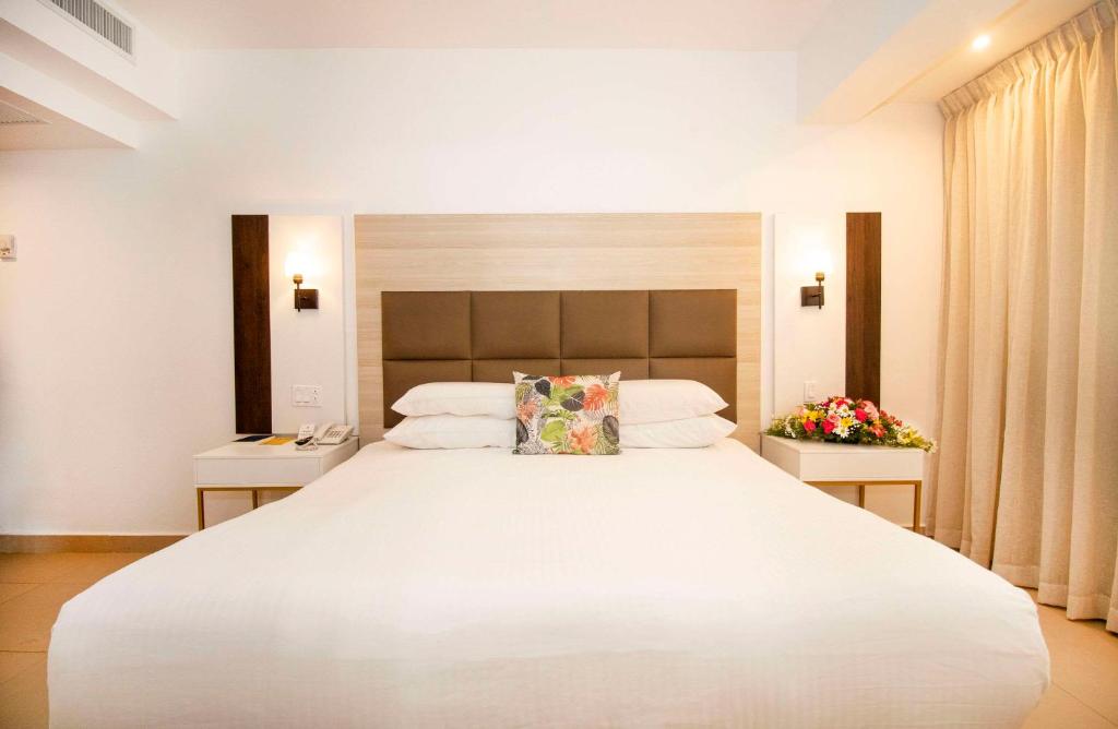 sypialnia z dużym białym łóżkiem i dwoma stołami w obiekcie Hotel Faranda Express Soloy and Casino, a member of Radisson Individuals w Panamie