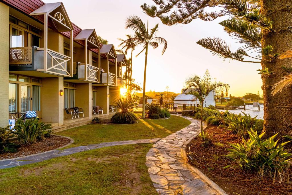 a resort with palm trees and a walkway at Comfort Resort Waters Edge in Port Macquarie