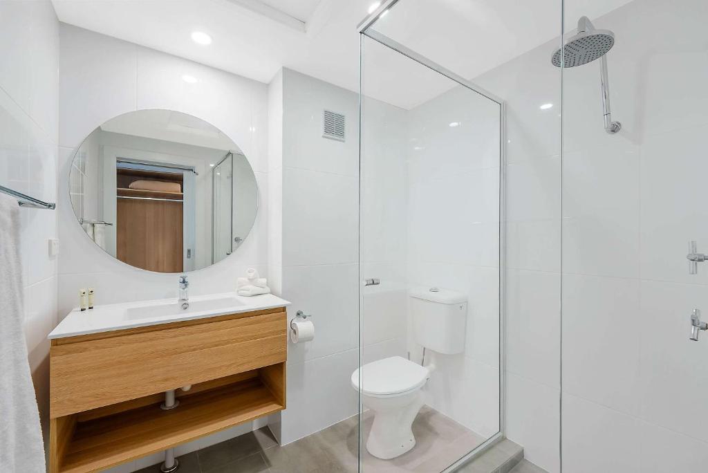 a bathroom with a toilet and a glass shower at Comfort Resort Waters Edge in Port Macquarie