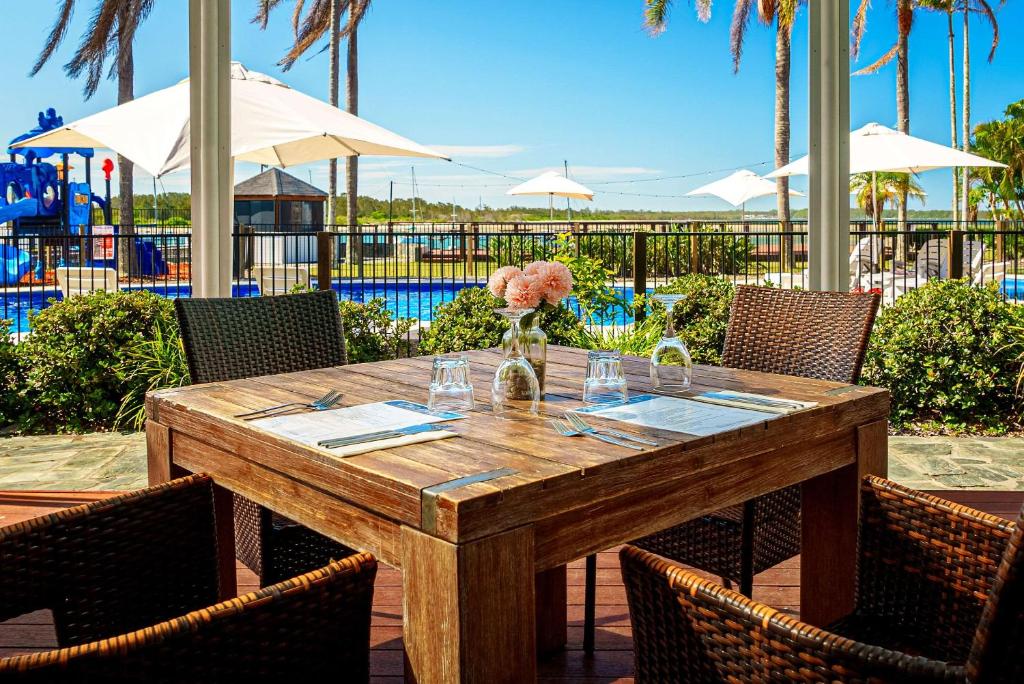 a wooden table with a vase of flowers on it at Comfort Resort Waters Edge in Port Macquarie