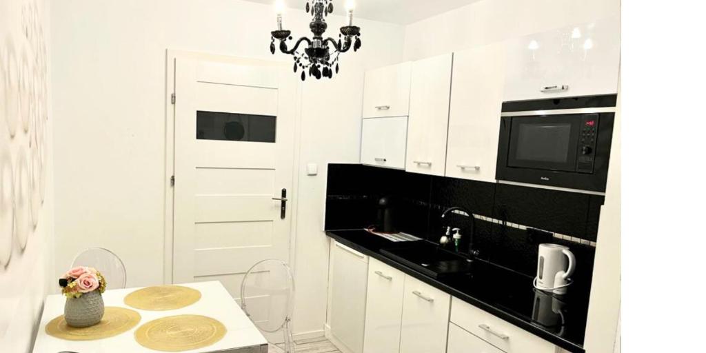 eine weiße Küche mit einem Tisch und einem Kronleuchter in der Unterkunft Apartament Kameralny15 in Danzig