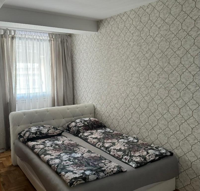 ein Bett in einem Schlafzimmer mit einer Wand in der Unterkunft Apartman City Center 1-šetalište in Prijedor