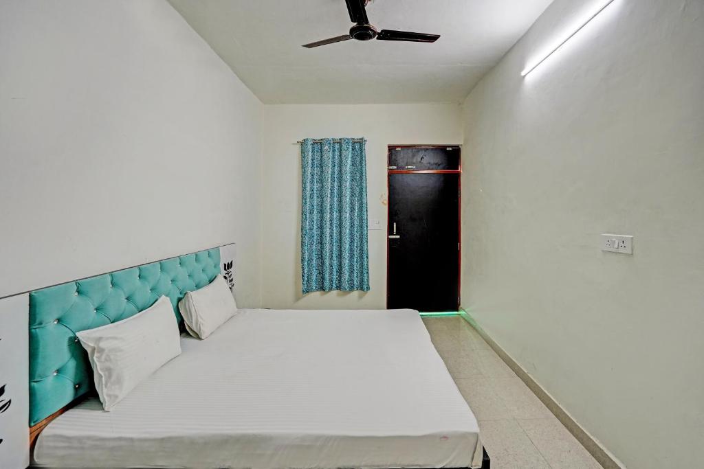 1 dormitorio con 1 cama con cabecero azul y ventana en Super OYO Chawla's Hotel & Restaurant, en Gurgaon