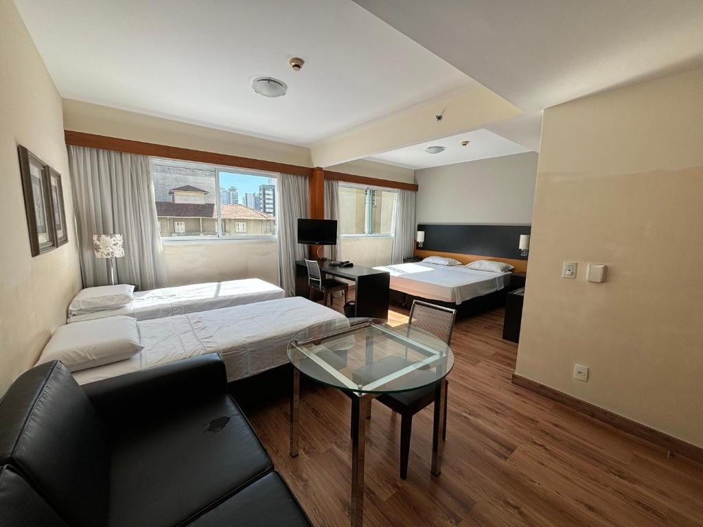a hotel room with two beds and a glass table at Flat 5 min Metrô Paraíso Av Paulista in Sao Paulo