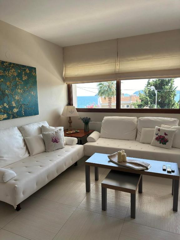 a living room with a white couch and a table at Navy View in Paleo Tsifliki