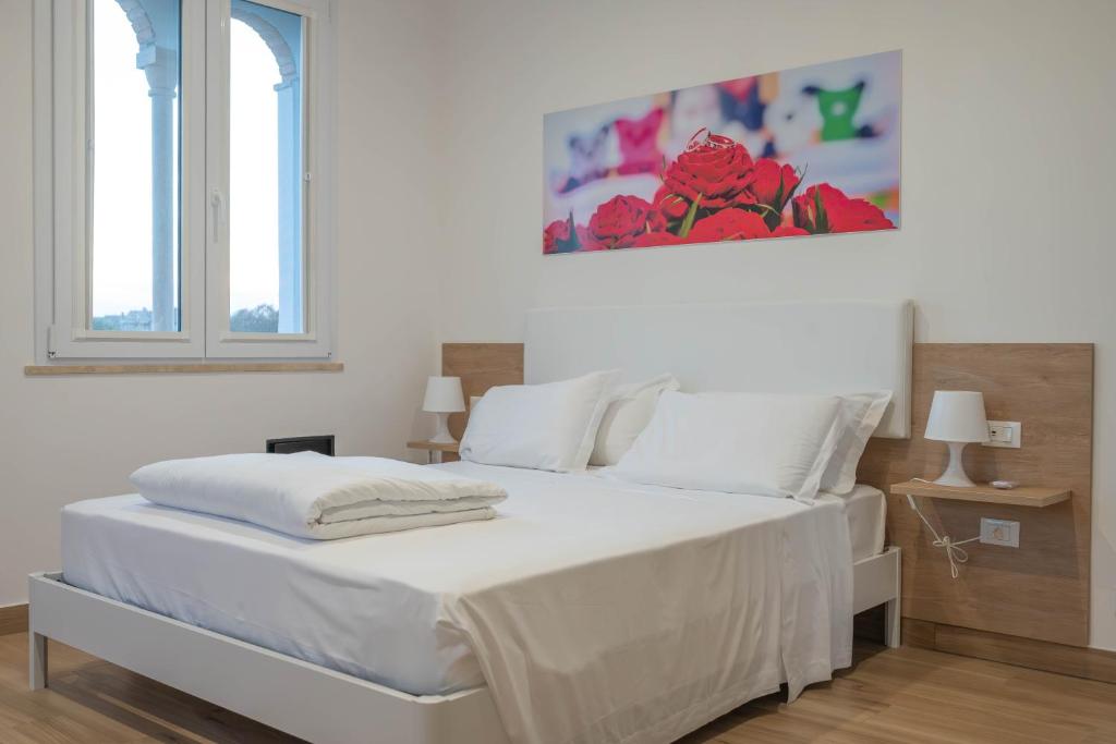 a white bedroom with a large bed with white sheets at DIMORA BORDIN Luxury Aparthotel Animali ammessi in Nettuno