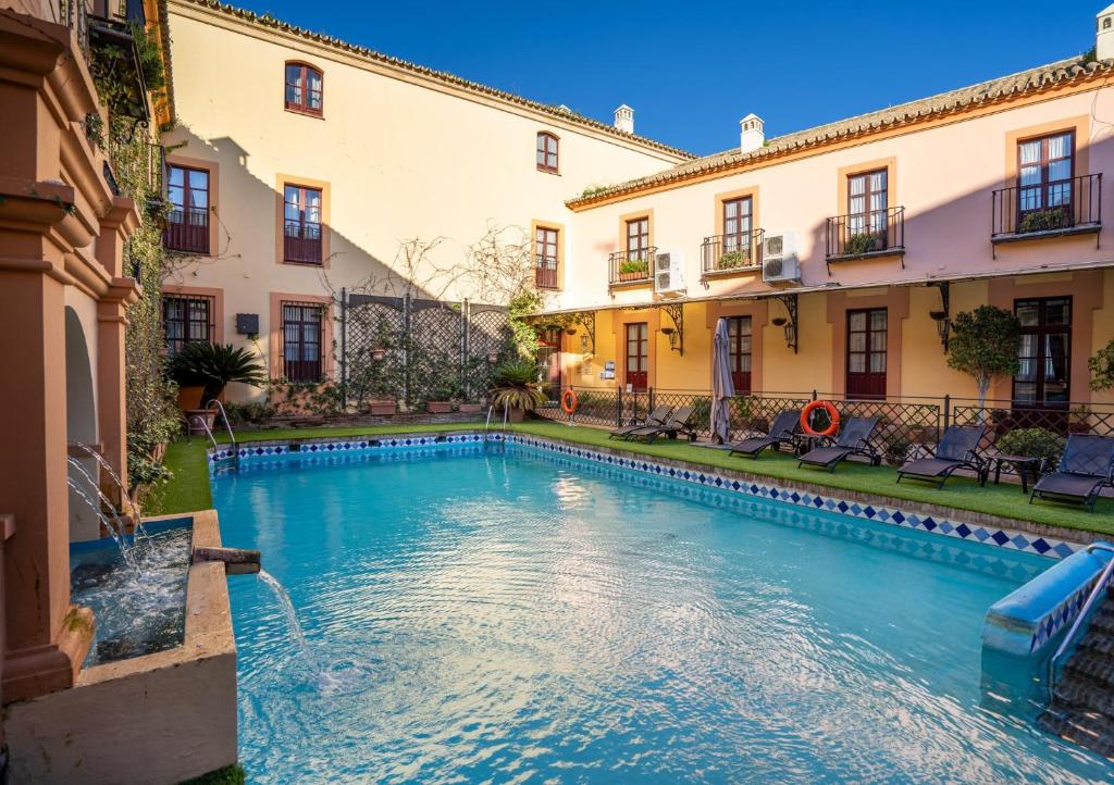 a swimming pool in the courtyard of a building at Hotel Alcázar de la Reina in Carmona