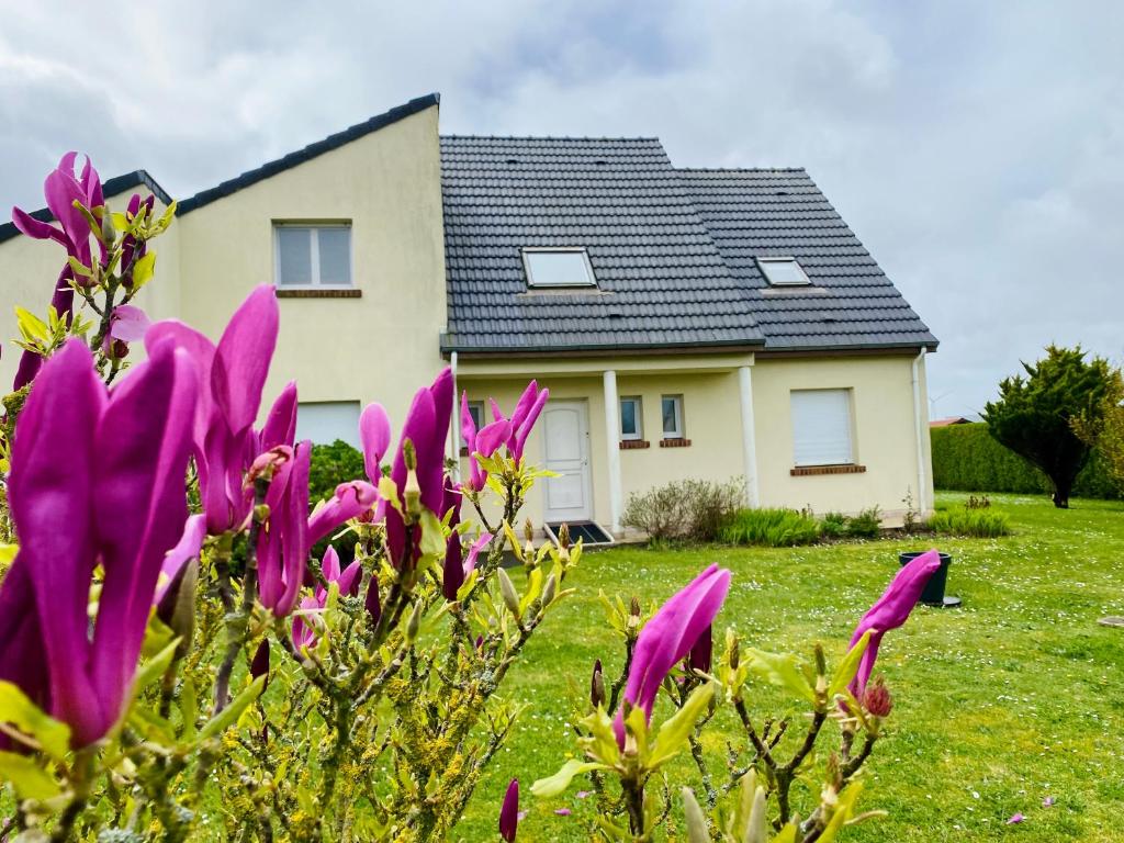a house with purple flowers in front of it at Chez Lucie et Compagnie pavillon familial avec beau jardin in Vron