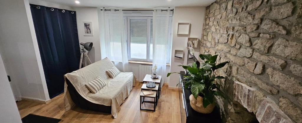 un salon avec un canapé et un mur en pierre dans l'établissement Le charme de la pierre, à Lorient