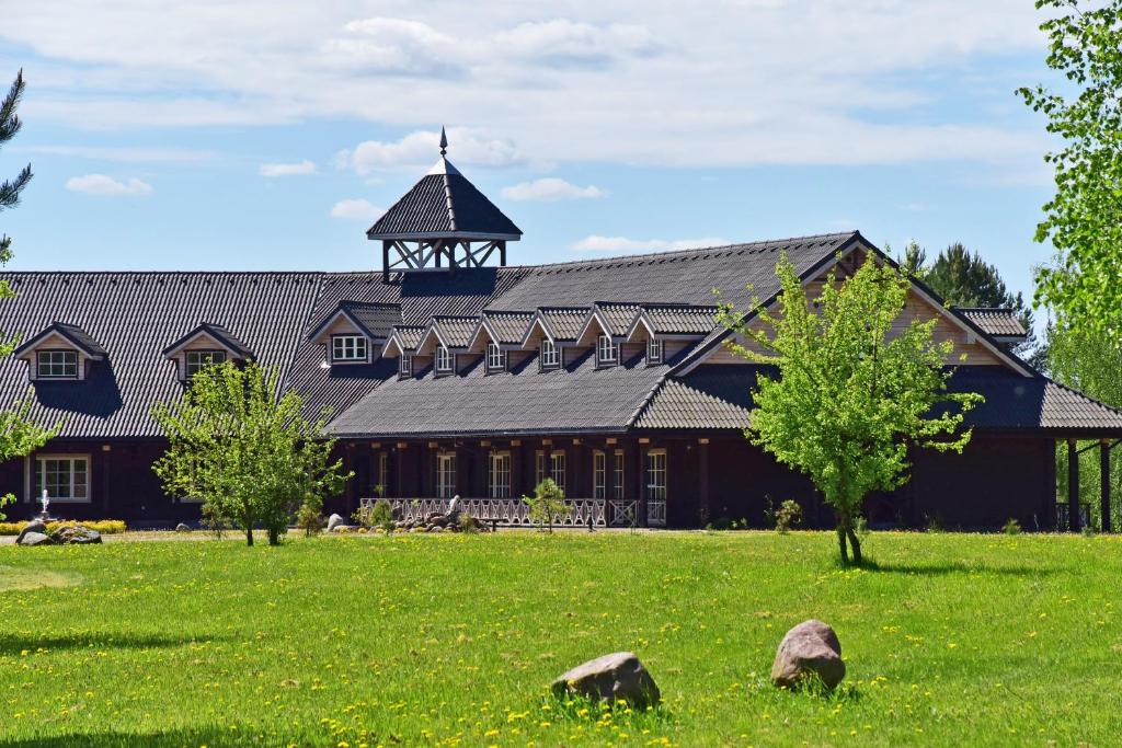 un grand bâtiment avec une tour au-dessus d'un champ dans l'établissement Pramogų ir konferencijų centras Paštys, à Vozgėliai