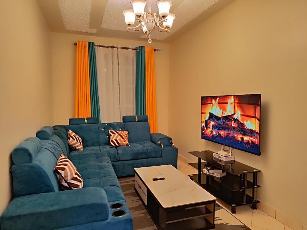 a living room with a blue couch and a tv at Romantic 1Bedroom Gateway in Kinoo in Kikuyu