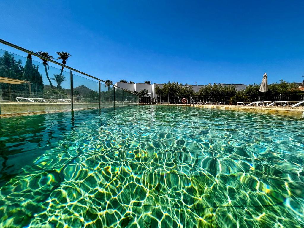 a swimming pool with clear blue water and a fence at Oro y Luz in Rodalquilar