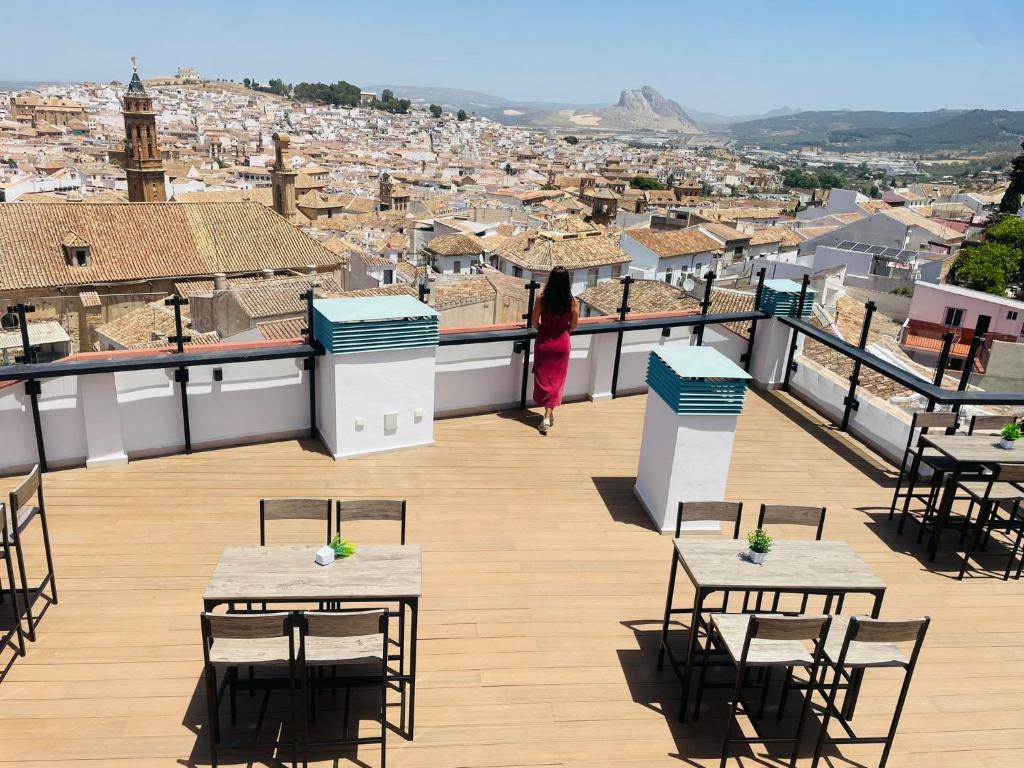 una donna che cammina su un balcone che si affaccia su una città di Apartamentos Antequera ad Antequera