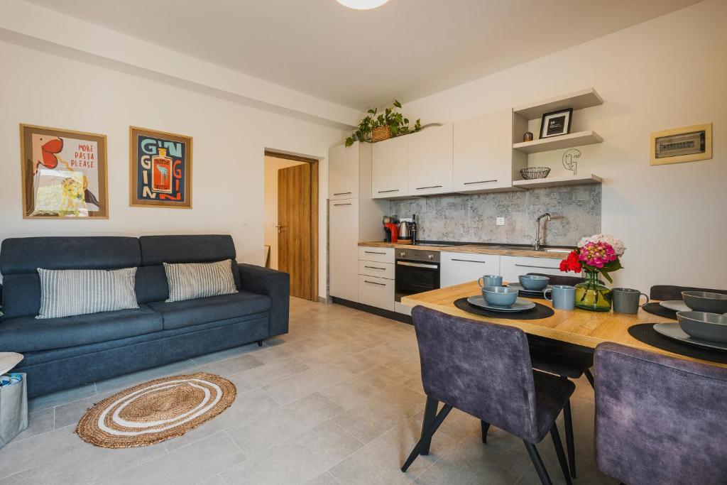 ein Wohnzimmer mit einem blauen Sofa und einem Tisch in der Unterkunft Apartments Olea in Novigrad Istria