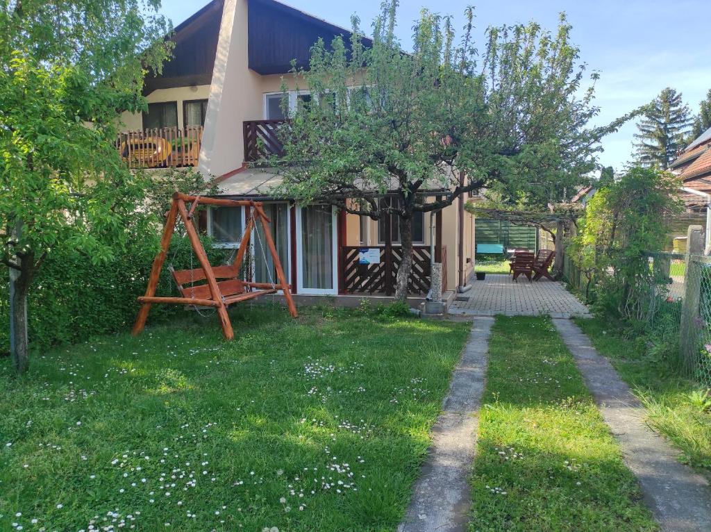 una casa con un árbol y un columpio en Tavasz apartman, en Balatonfenyves