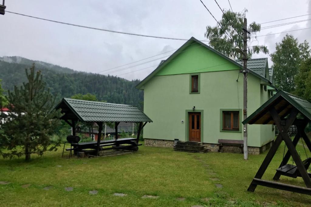 una casa verde con una mesa de picnic delante de ella en Goryanka Hotel, en Mykulychyn