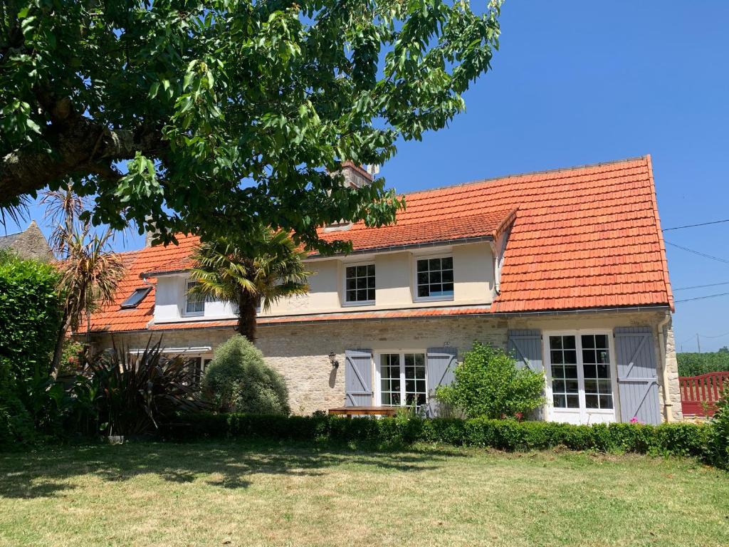 une maison ancienne avec un toit orange dans l'établissement Longère bord de mer avec grand jardin fleuri, à Géfosse-Fontenay