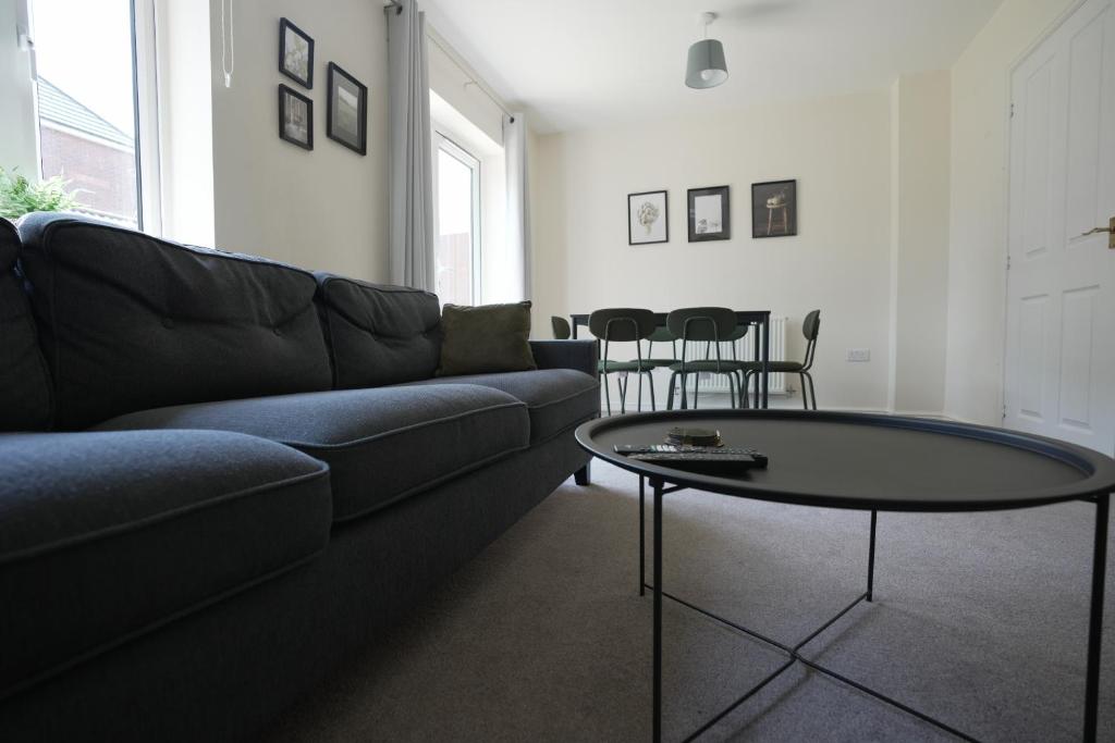 een woonkamer met een bank en een tafel bij Spacious 4 bedroom, perfect for contractors, families, private parking in Royal Wootton Bassett