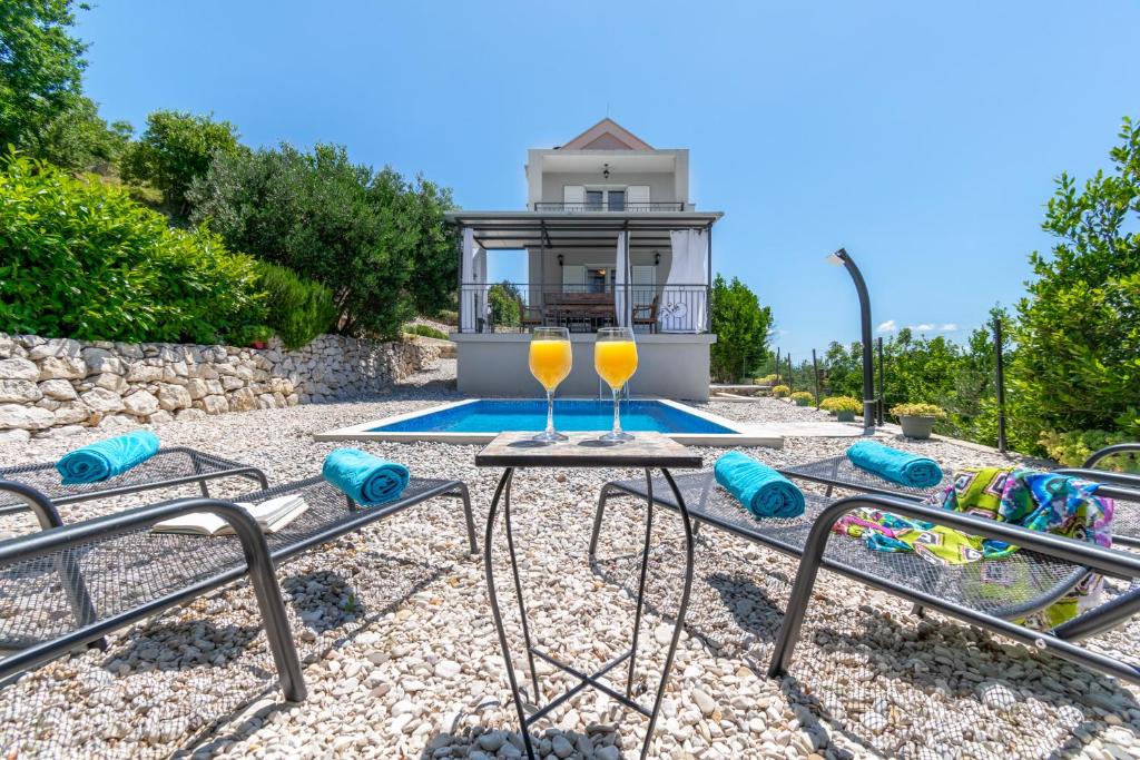 a pair of wine glasses on a table next to a pool at Villa with Sea View - Private Heated Pool in Podgora