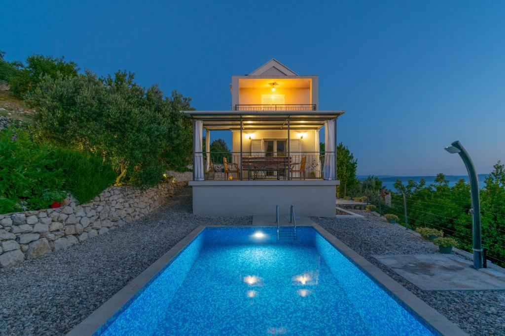 a villa with a swimming pool in front of a house at Villa with Sea View in Podgora