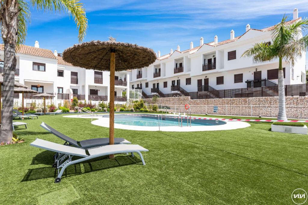 a chair and an umbrella in a yard with a pool at ViVi Homes - El Sembrador Pool, Terrace & Golf in La Cala de Mijas