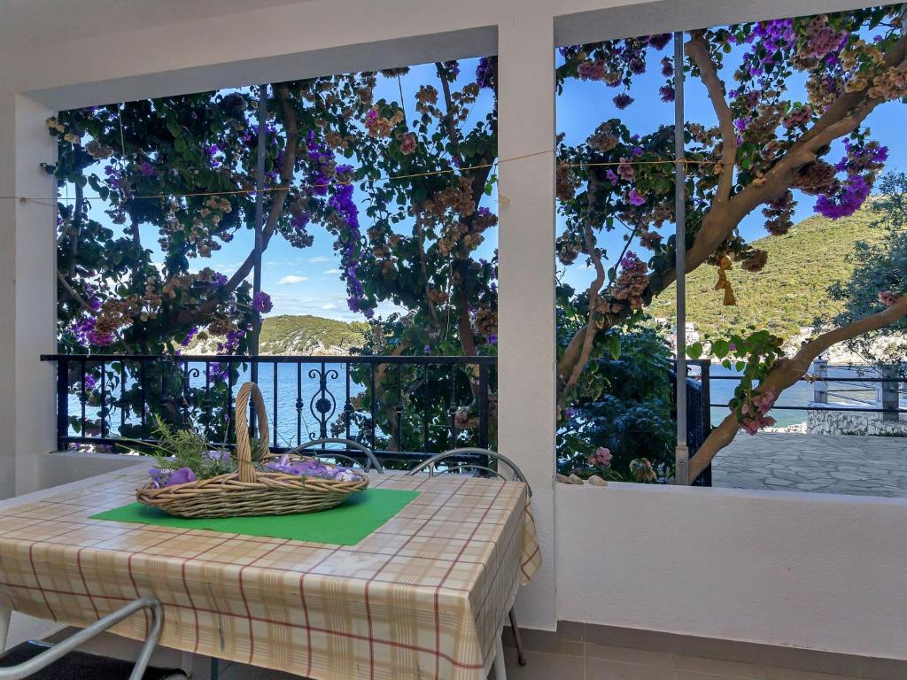 a table with a basket of flowers on it in front of a window at Apartment Rubin-2 by Interhome in Zastražišće