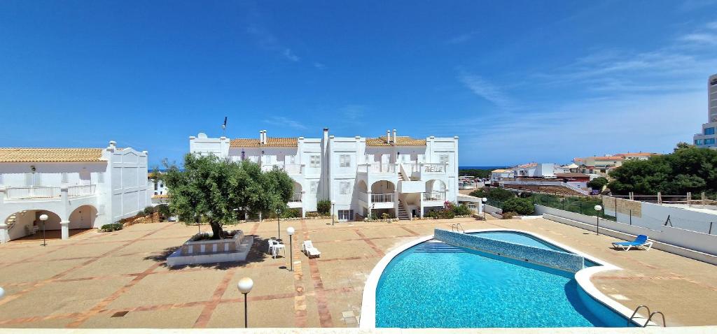 a swimming pool in front of a white building at Apartamento 314 Castell Sol in Arenal d'en Castell