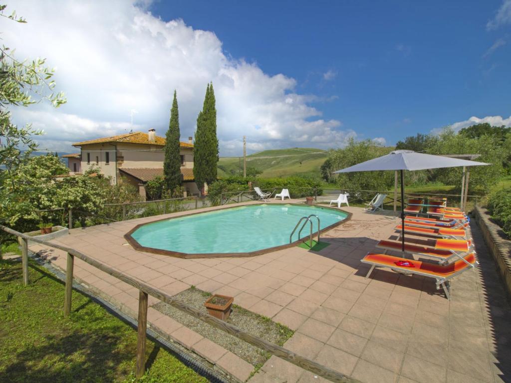 a pool with chairs and an umbrella and a house at Holiday Home Villa Etrusca by Interhome in Volterra