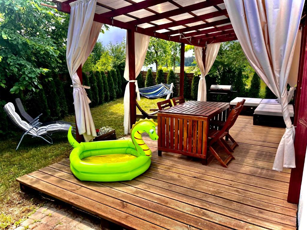 una terraza de madera con una silla verde y una mesa en Noclegi na Mazurach nad Jeziorem, en Regiel