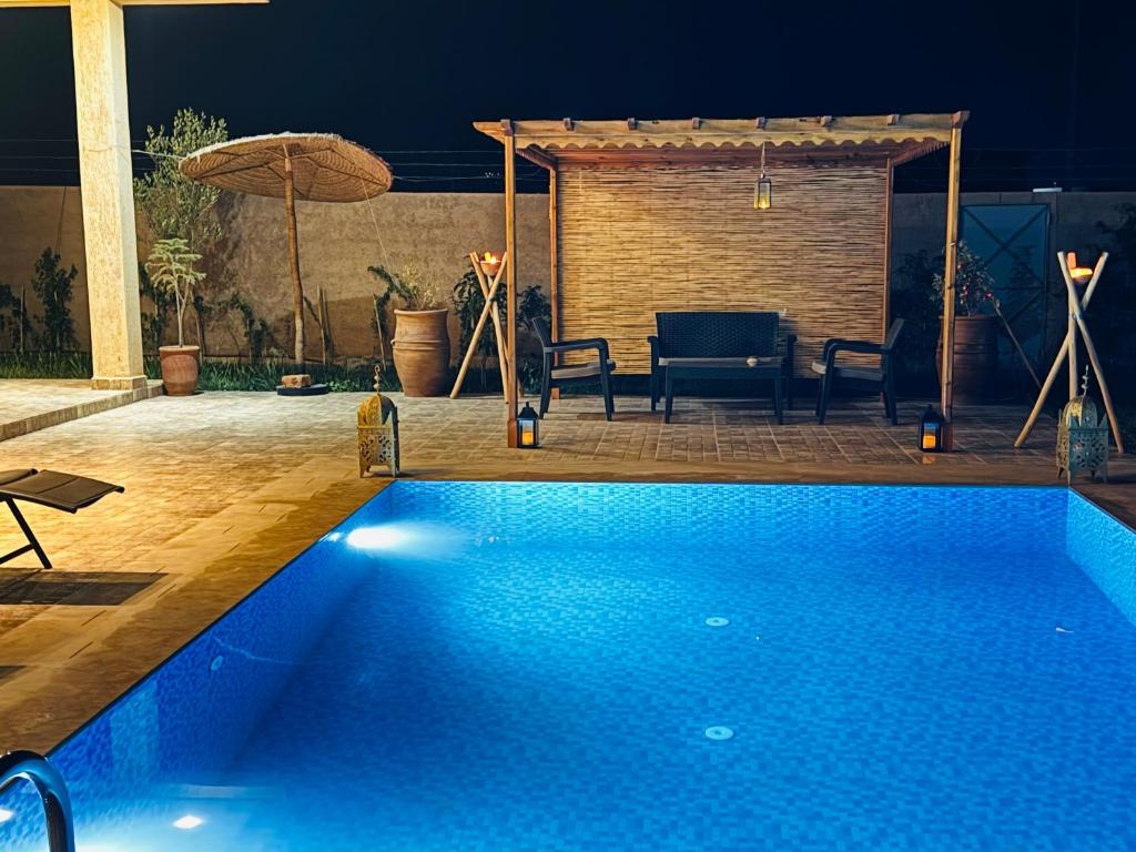 - une piscine bleue avec une table et un parasol dans l'établissement Peaceful Pool Villa, à Marrakech