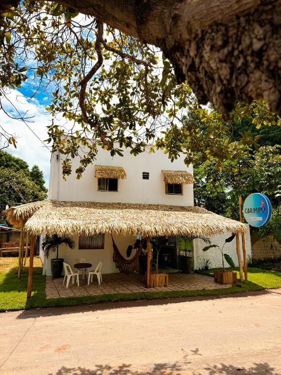 un petit bâtiment blanc avec un toit en paille dans l'établissement Carimbó Pousada e Hostel, à Alter do Chão