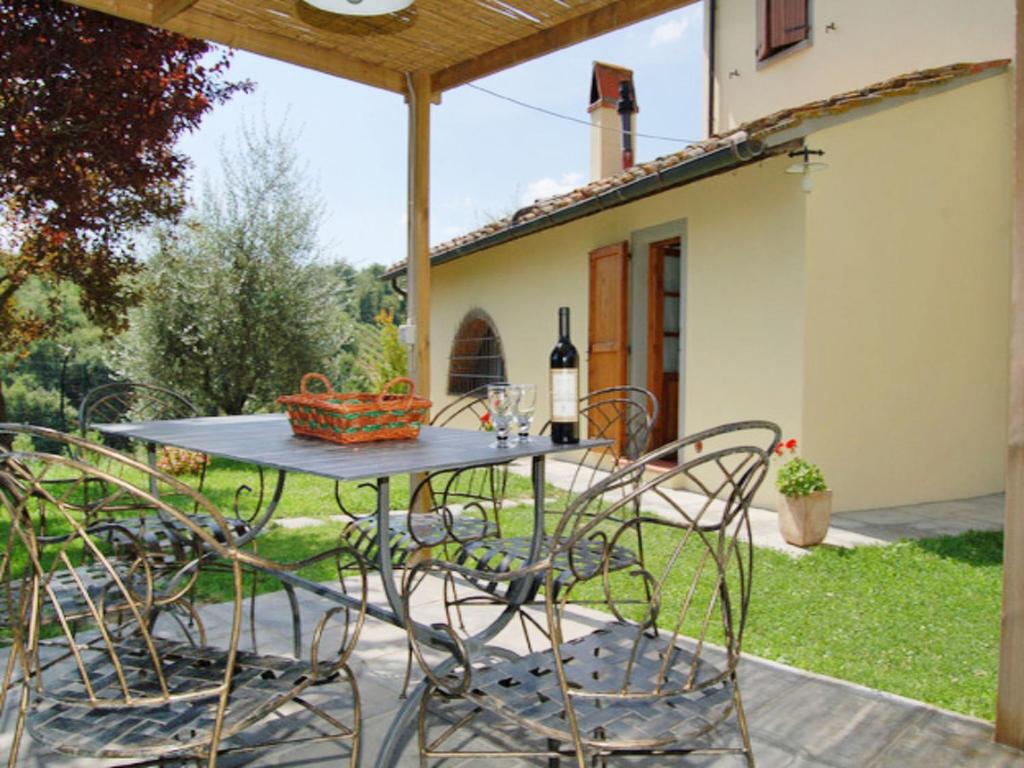 a patio table with chairs and a bottle of wine at Apartment Arco by Interhome in Podere Panzano