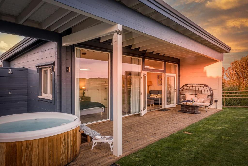 una terraza con bañera de hidromasaje en una casa en Rafters Lodge, Nr Saunton, en Georgeham