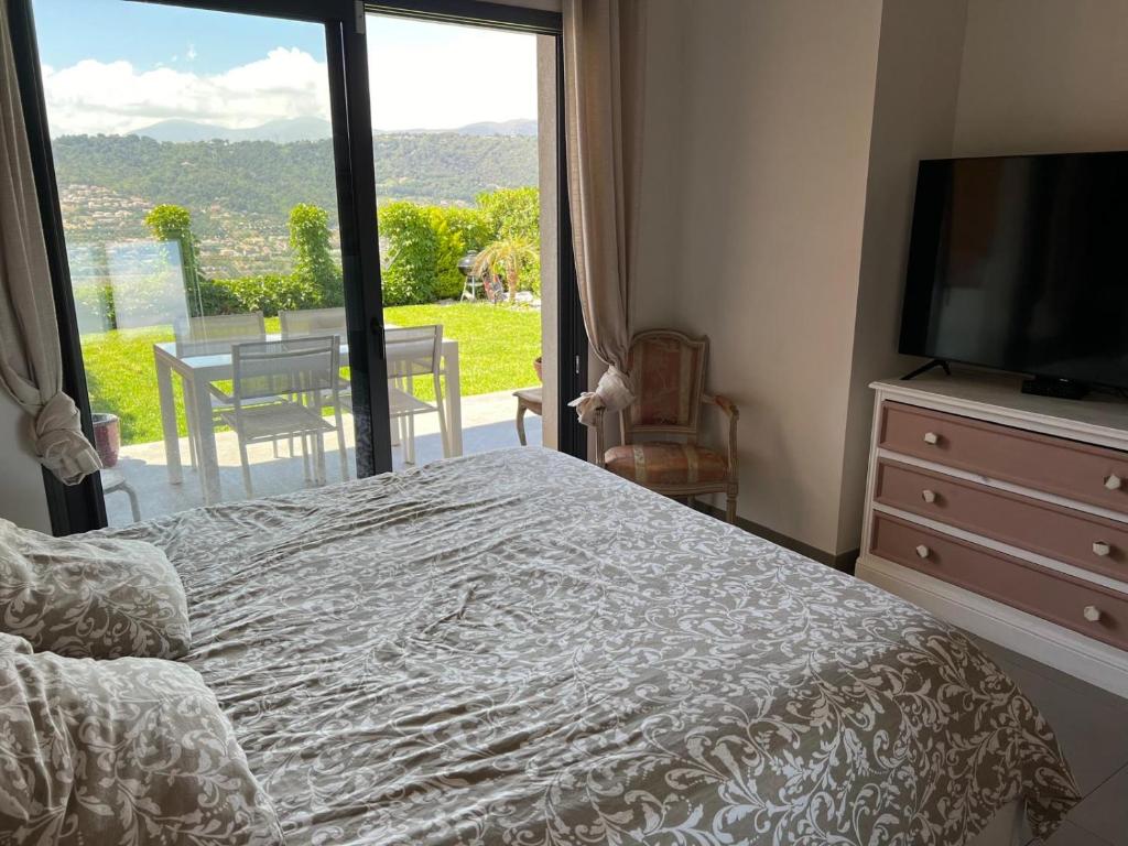 une chambre avec un lit et une télévision et un balcon dans l'établissement Joli 3 pièces ensoleillé sur les hauteurs de Nice, à Nice