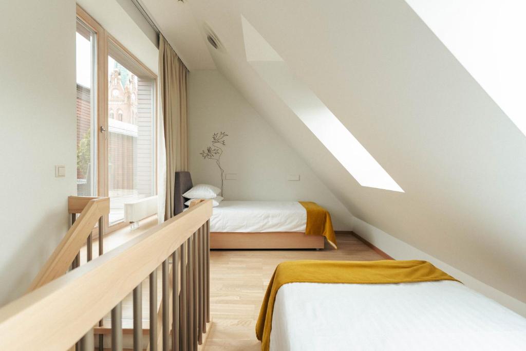 a attic bedroom with two beds and a staircase at Amberton Green Apartments Palanga in Palanga